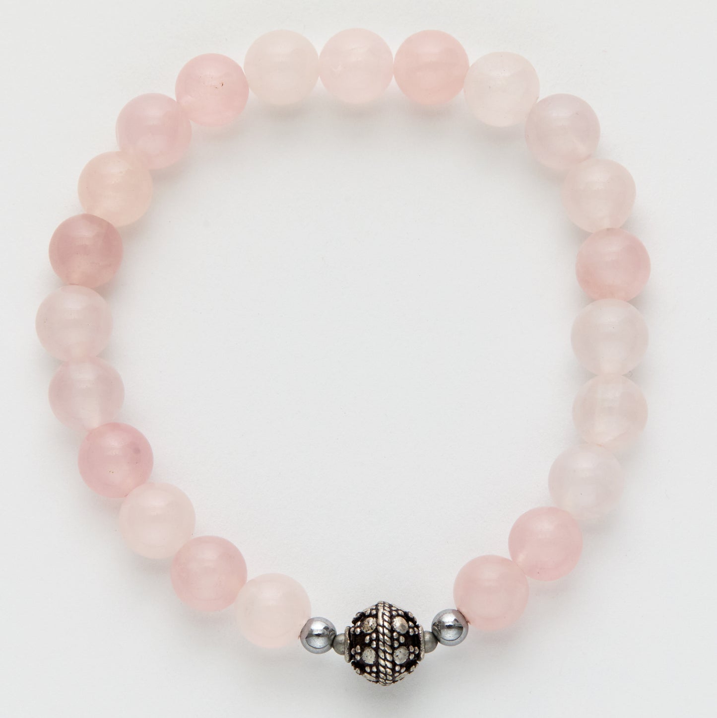 Pink beaded bracelet with a silver and black charm on a white background