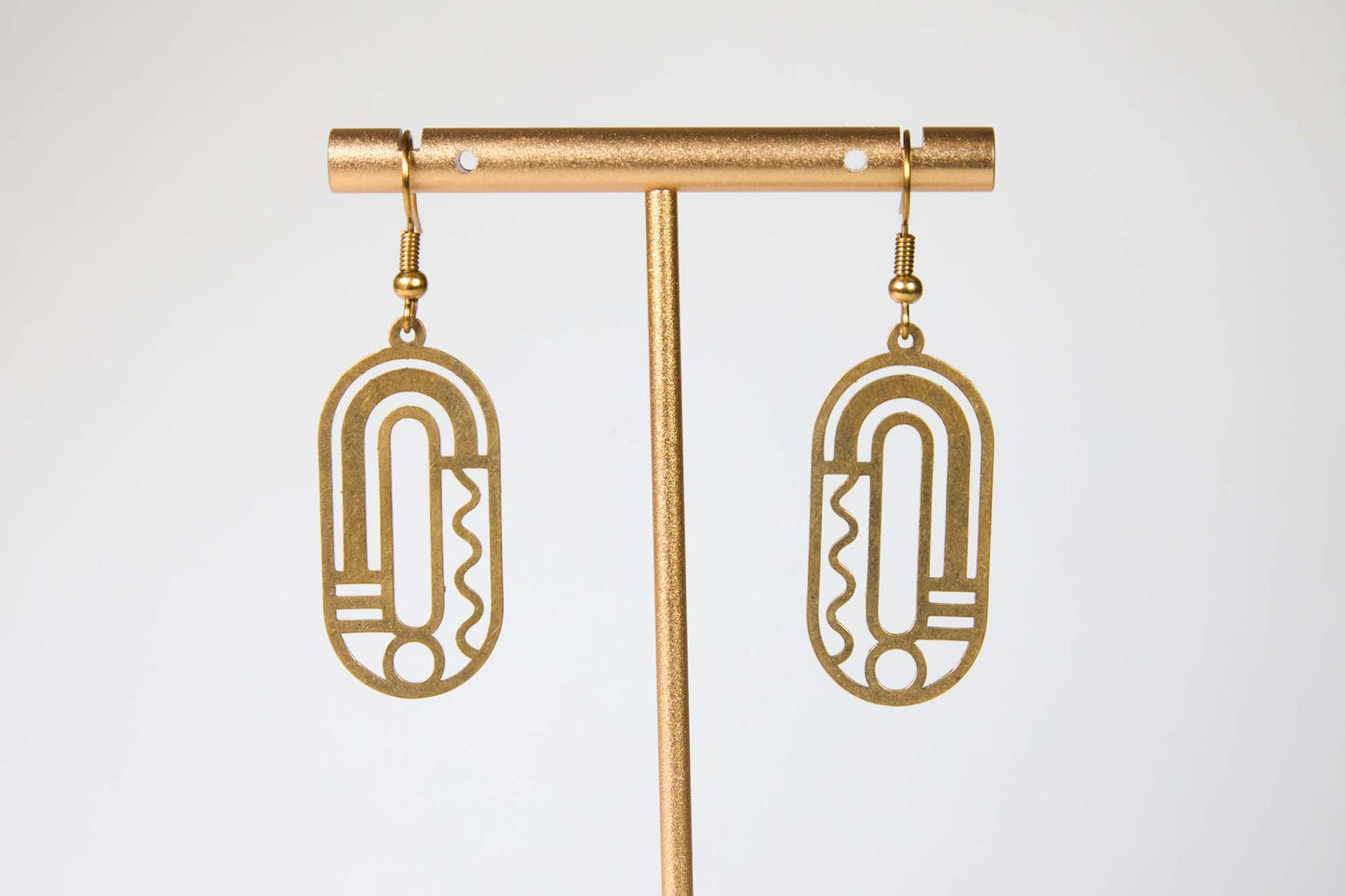 Gold earrings with geometric design on a white background