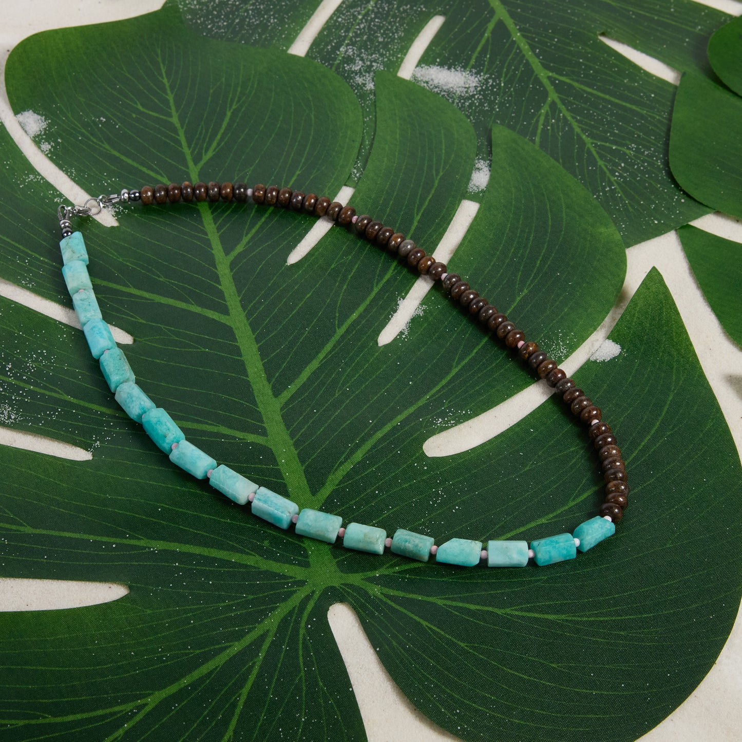 Necklace with amazonite and bronzite beads on a green leaf