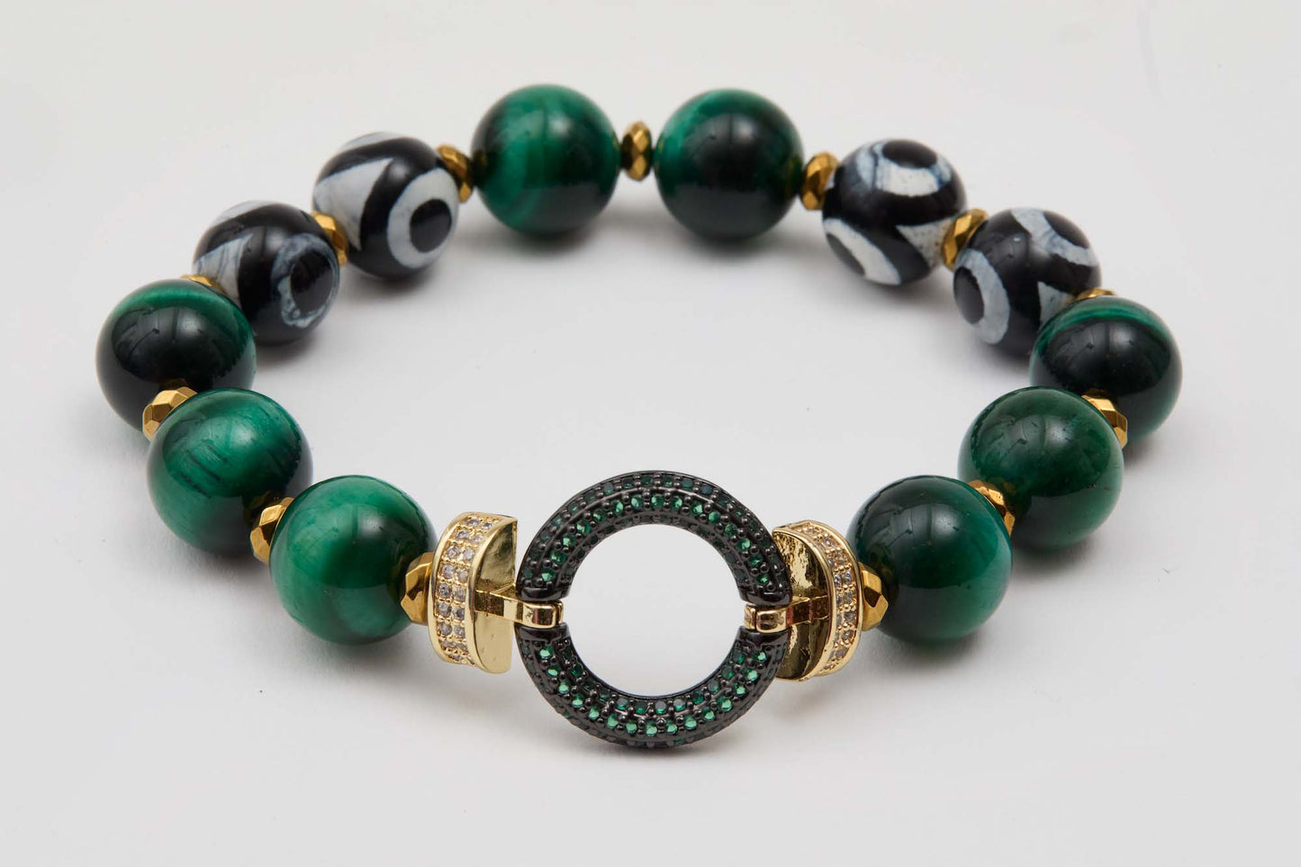Bracelet with green and black beads and a gold, green, and black connector on a white background