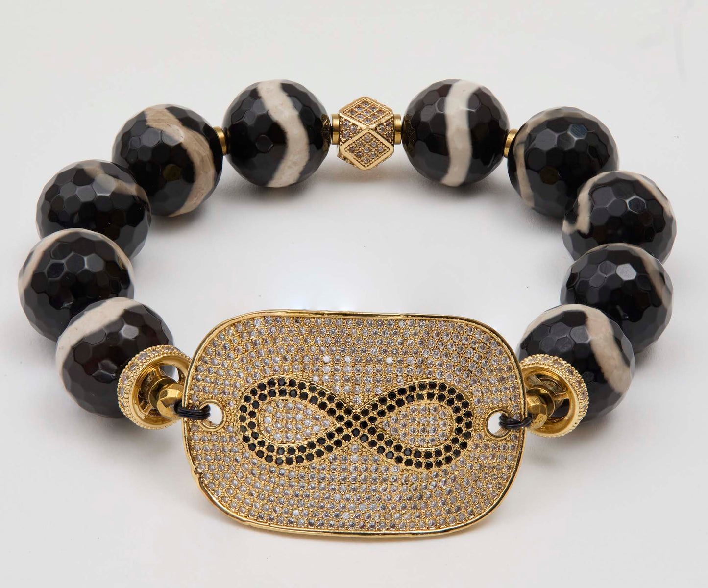 Bracelet with black and white beads and a gold infinity symbol focal on a white background
