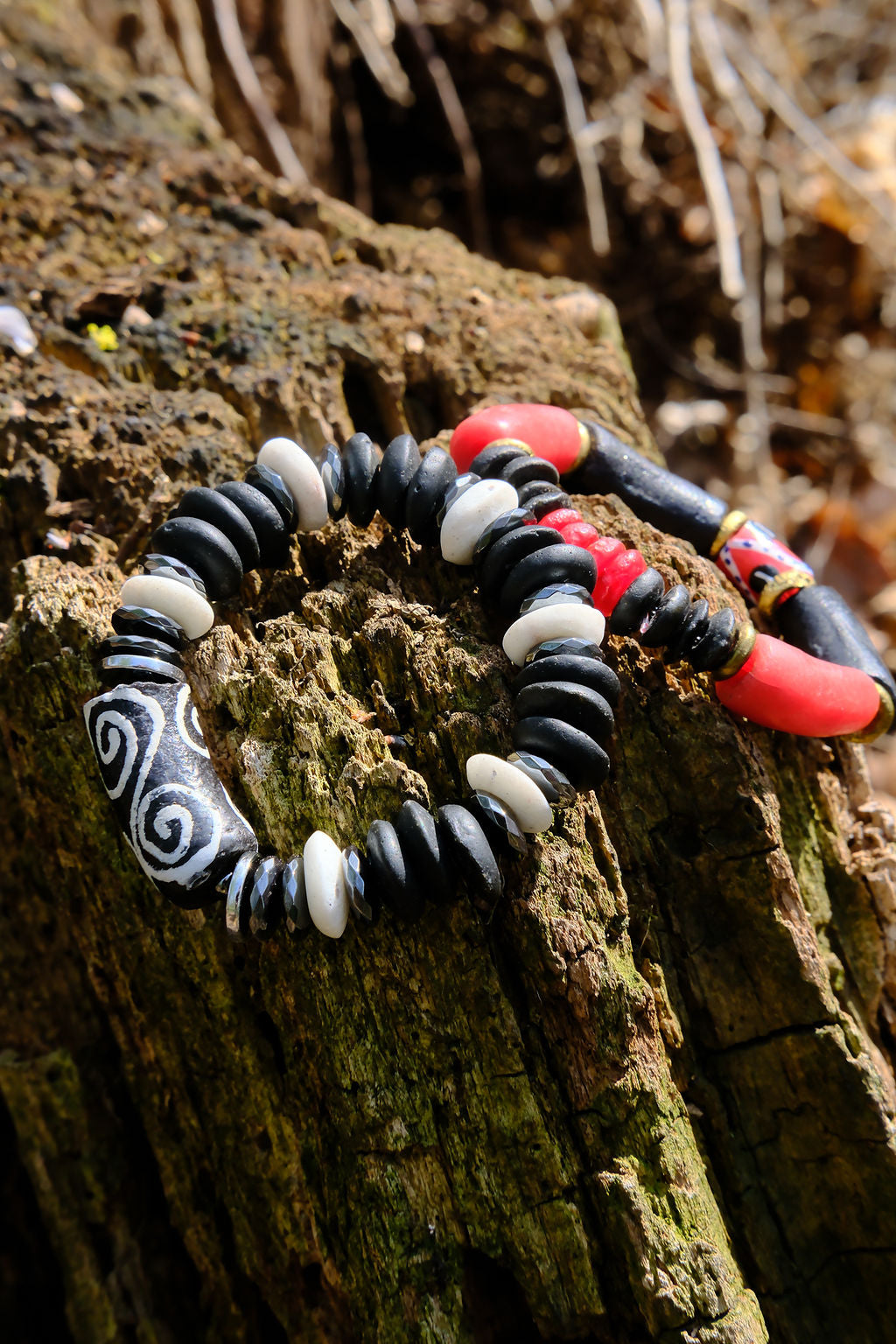 Two bracelets with black, white, and red beads on a wooden surface