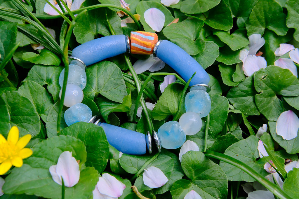 Blue beaded bracelet on green leaves with flowers