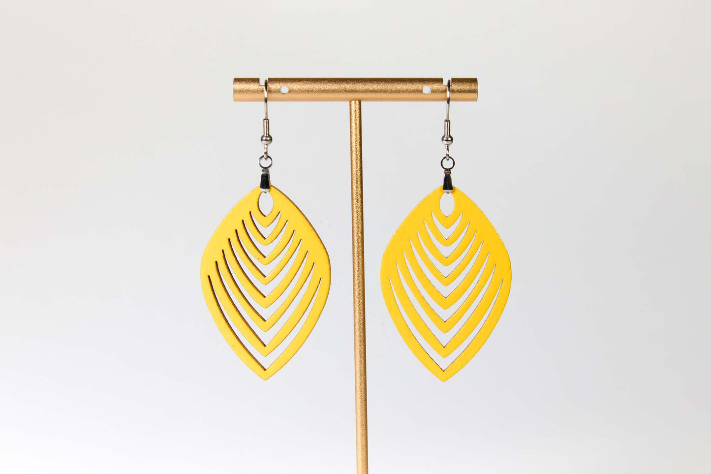 Yellow earrings on a gold earring stand against a white background