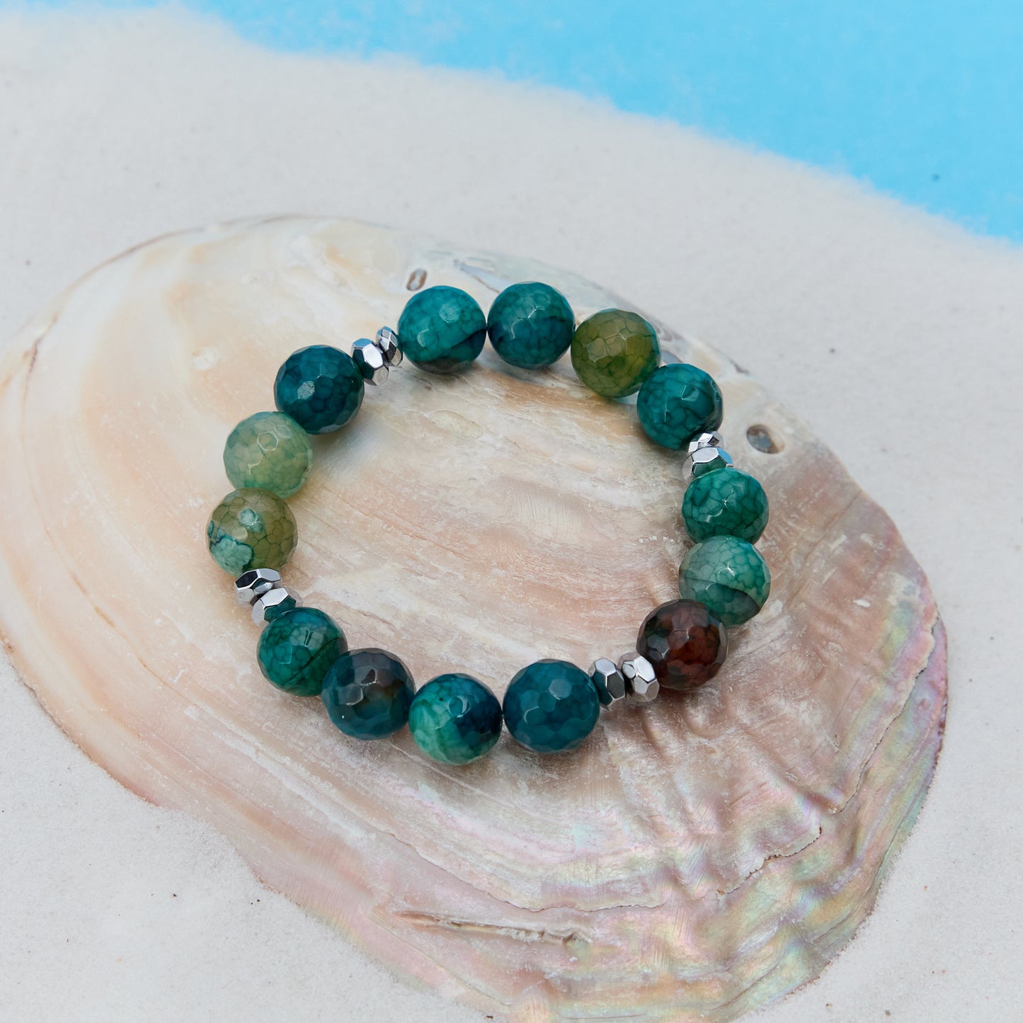 Green beaded bracelet on a large shell with a blue background