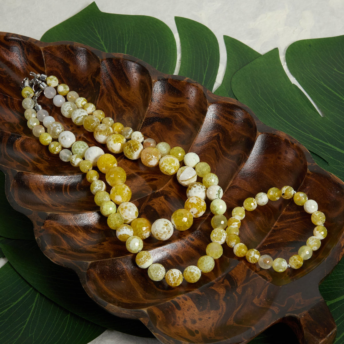 Yellow necklaces and bracelet on wooden leaf tray