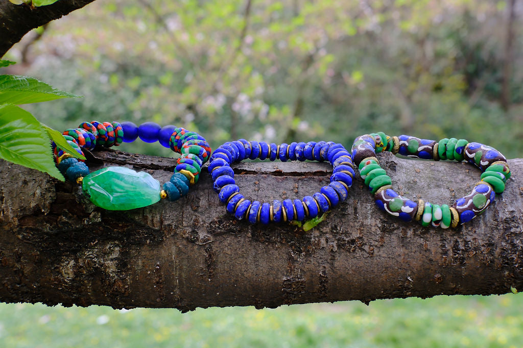 three blue and green bead bracelets on a tree branch