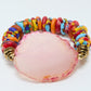 Colorful beaded bracelet with a pink central stone on a white background