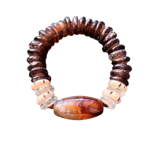 A handmade beaded bracelet featuring dark brown textured beads, clear faceted spacer beads, and a large polished oval agate bead in the center with natural brown and orange patterns, set against a plain white background.