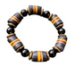 A beaded stretch bracelet featuring alternating matte black round beads and textured cylindrical beads with a dark gray/black base and orange-yellow stripes, separated by small gold spacers, on a plain white background.