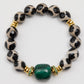 Bracelet with black and white patterned beads and a green gemstone on a white background