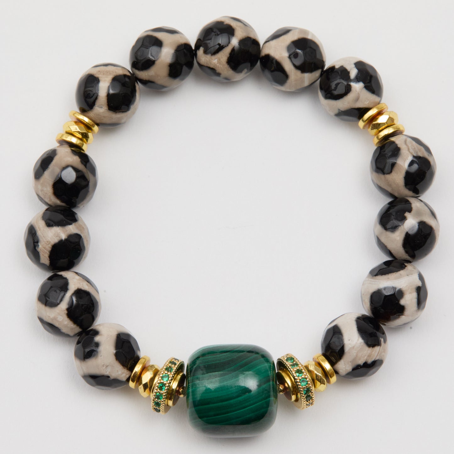 Bracelet with black and white patterned beads and a green gemstone on a white background