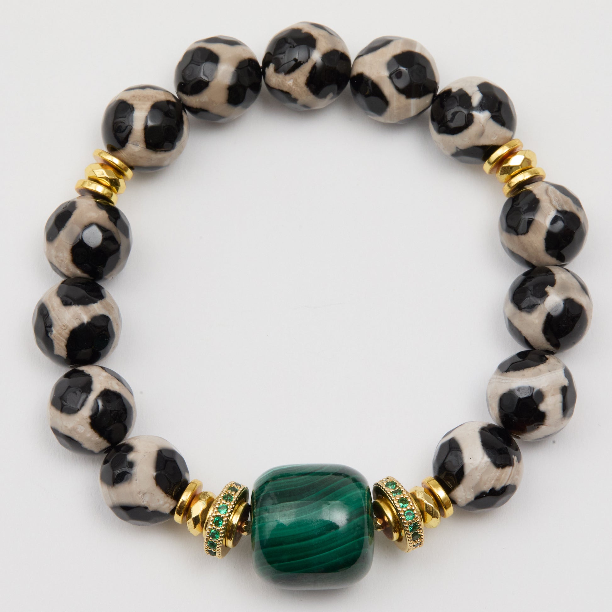Bracelet with black and white patterned beads and a green gemstone on a white background
