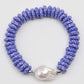 Bracelet with blue and white patterned beads and a large pearl on a white background