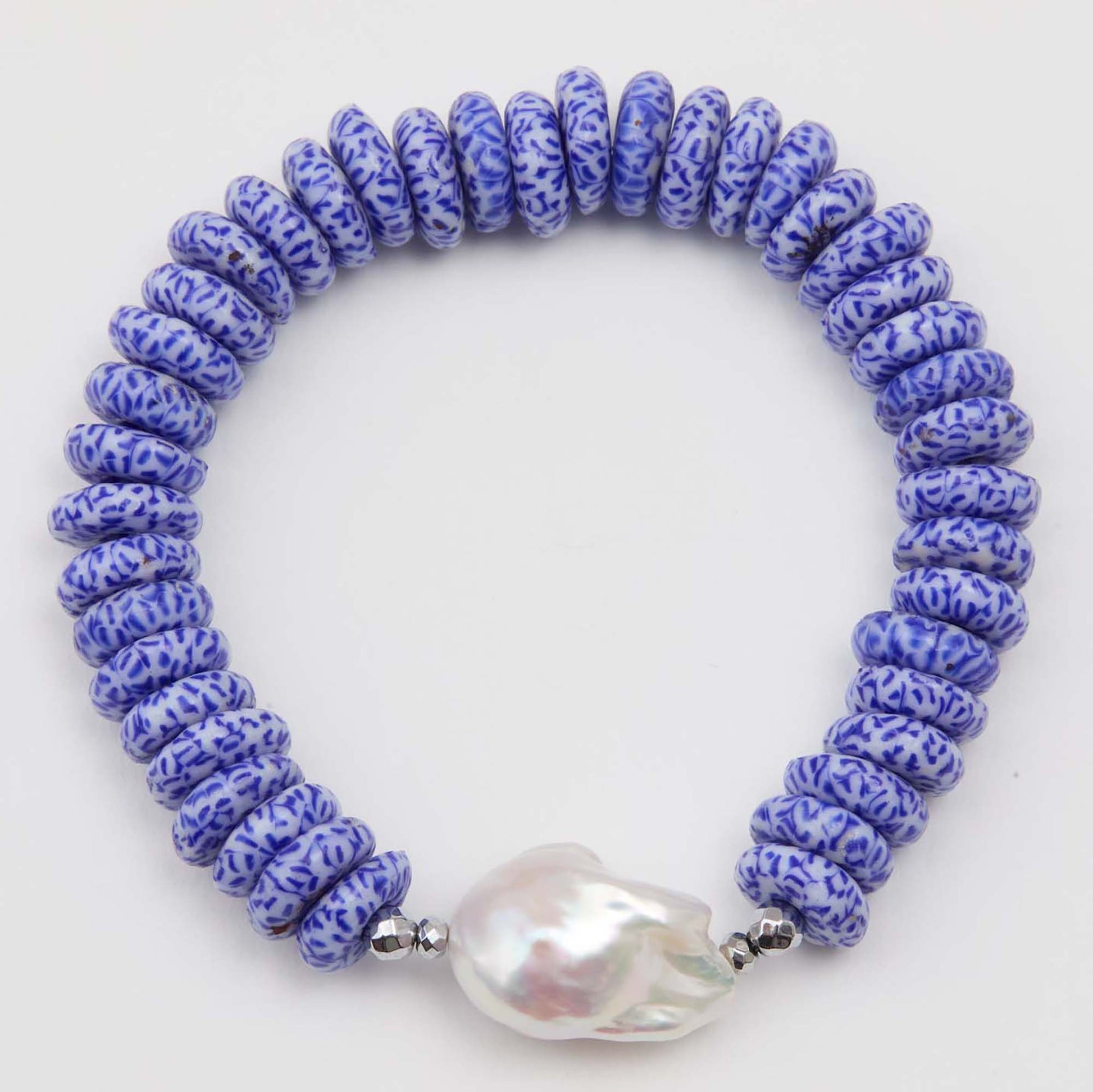 Bracelet with blue and white patterned beads and a large pearl on a white background