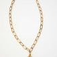 Gold chain necklace with a purple gemstone pendant on a white background