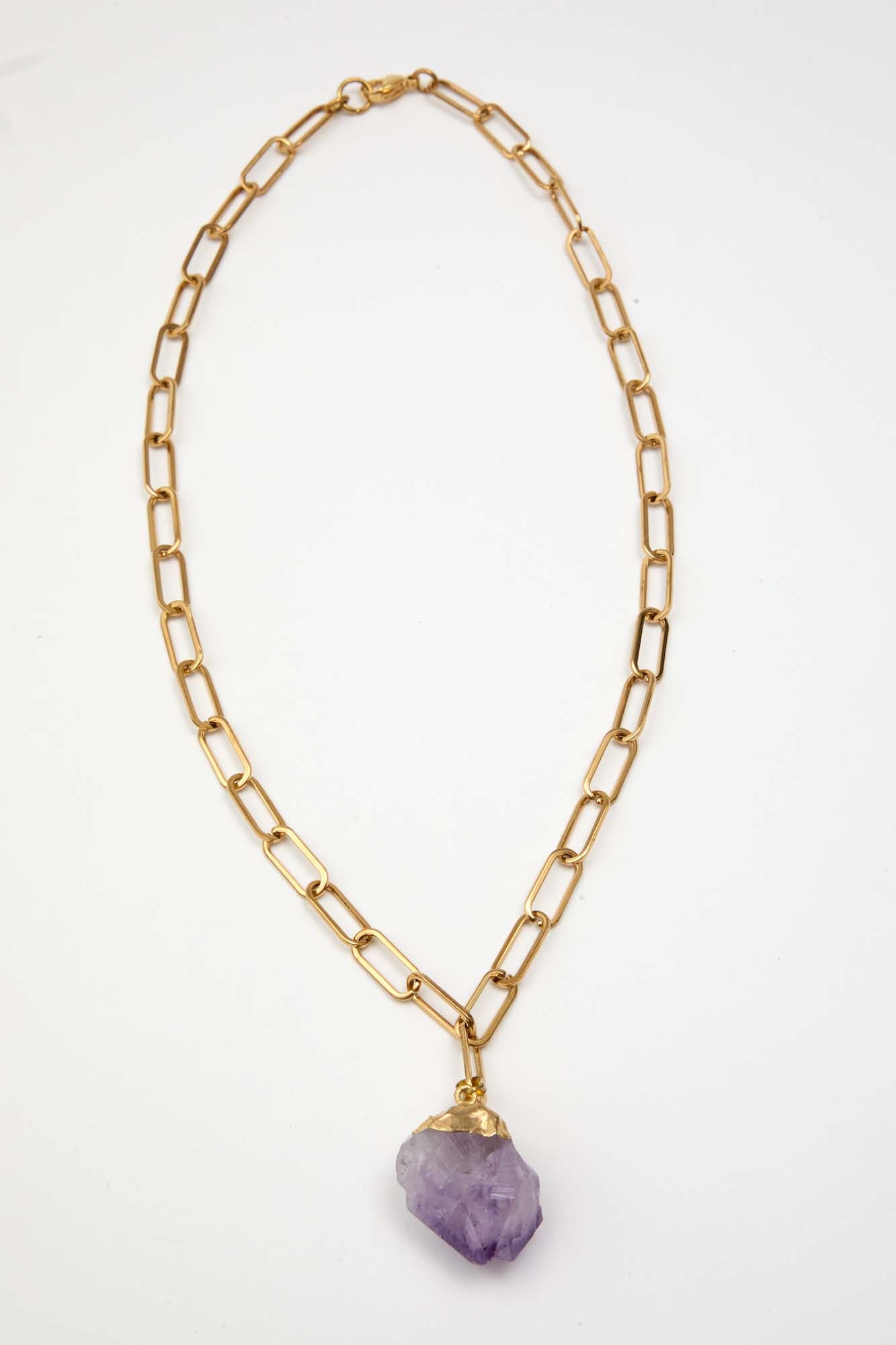 Gold chain necklace with a purple gemstone pendant on a white background