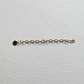 A delicate gold chain extender with a small round gold disc charm, laid horizontally on a textured white canvas background.