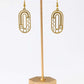 Gold earrings on a matching gold stand against a white background