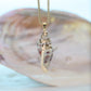 Shell pendant necklace on a blurred shell background