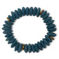 A beaded stretch bracelet made of dark teal-blue Ashanti beads with brass spacer beads, shown on a plain white background.
