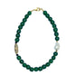 A hunter green beaded necklace with a brass focal bead and a baroque pearl, featuring hematite spacers and lampwork glass beads.