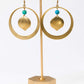Gold hoop earrings with turquoise beads on a gold stand against a white background