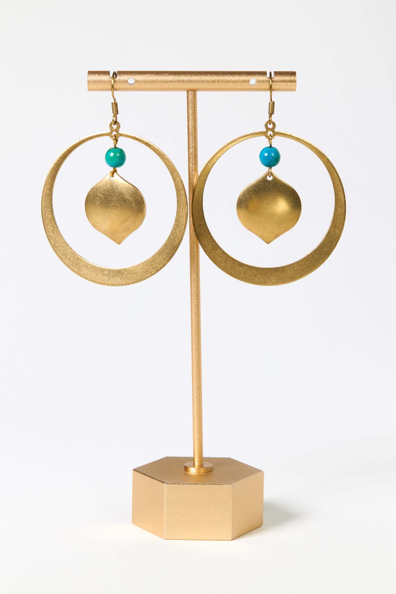 Gold hoop earrings with turquoise beads on a gold stand against a white background