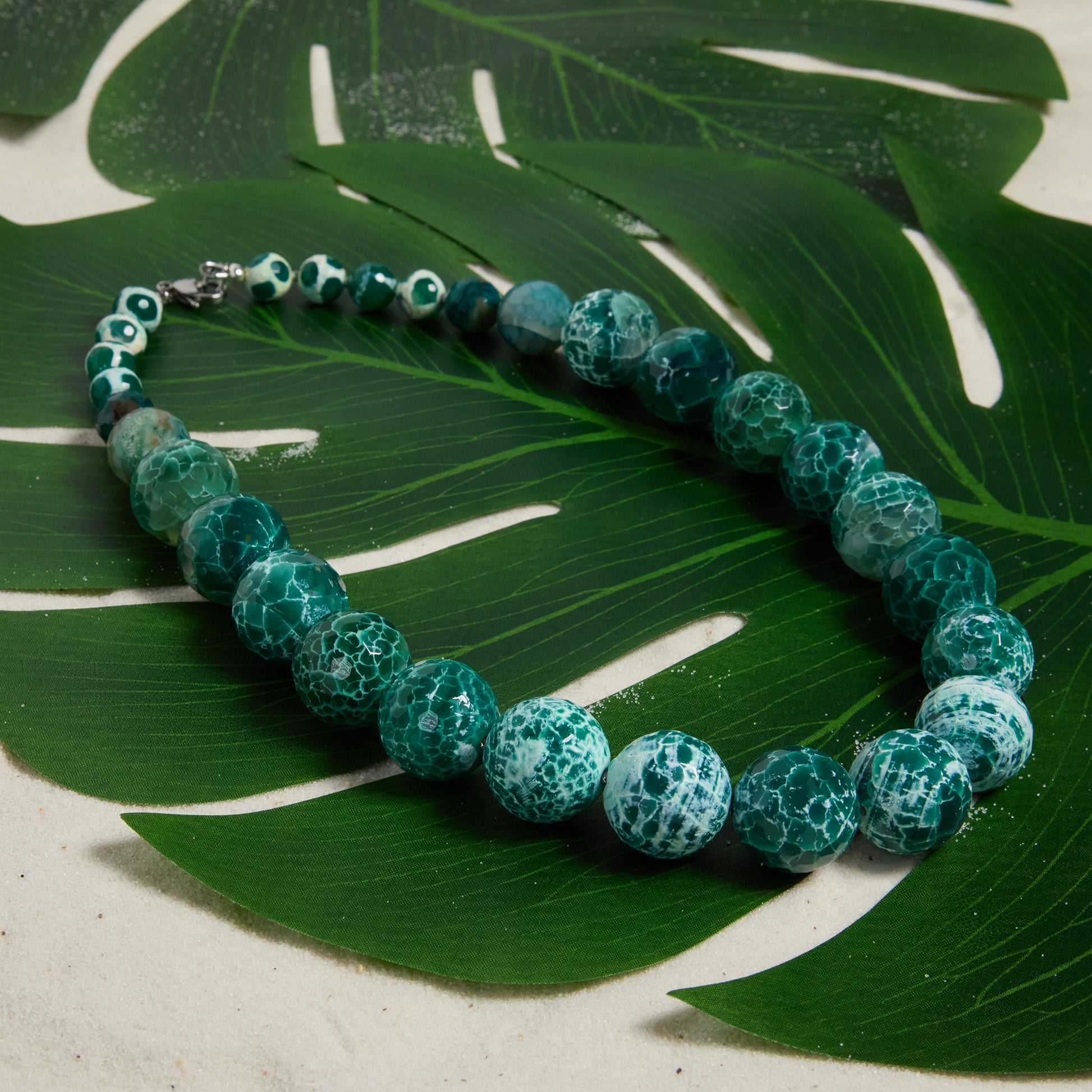 Green beaded necklace on a green leaf