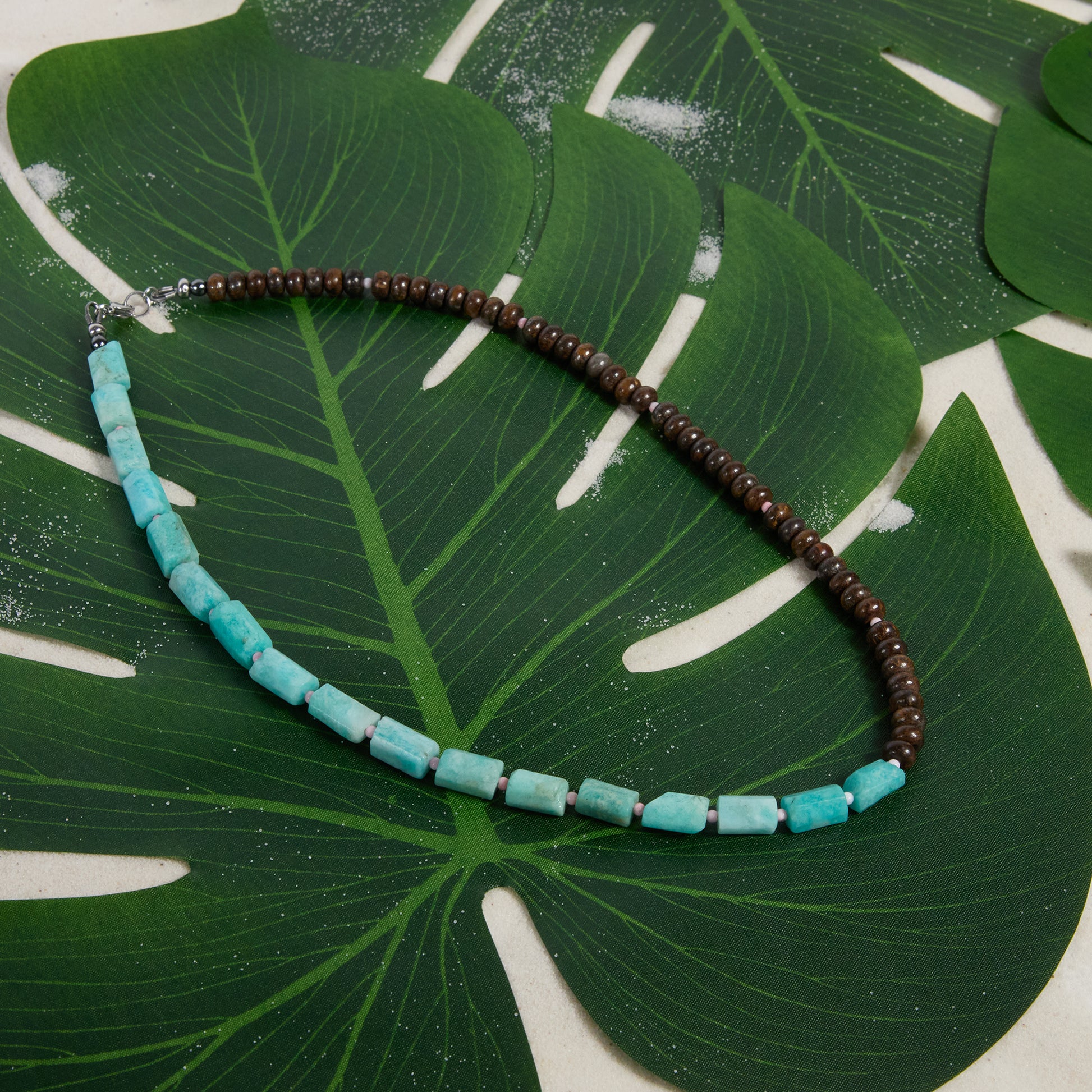 Necklace with amazonite and bronzite beads on a green leaf