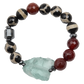 Beaded bracelet with red, black, and white beads and a large green stone on a white background