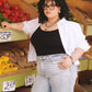 Person standing in a produce section with vegetables and boxes in the background