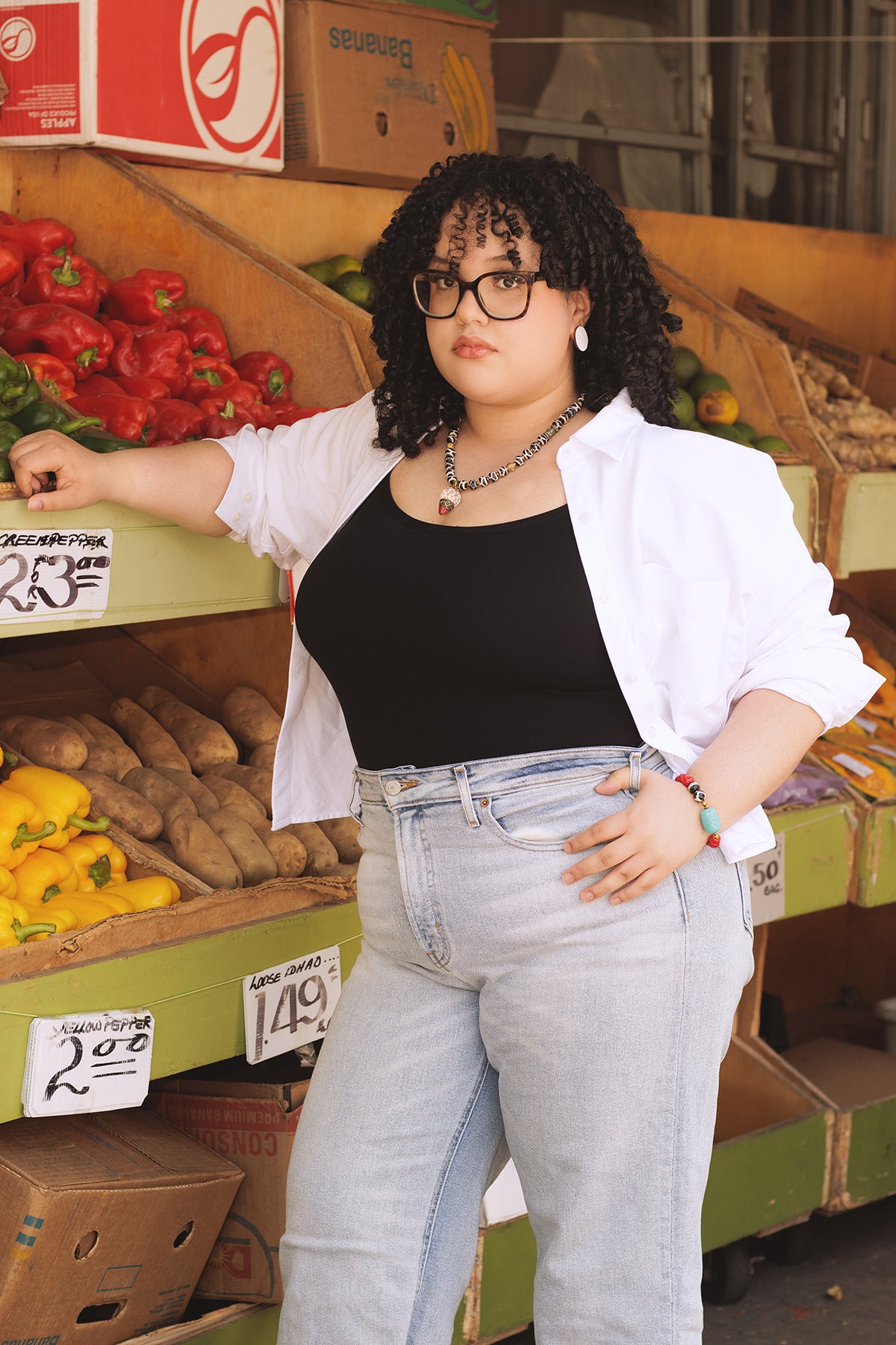 Person standing in a produce section with vegetables and boxes in the background