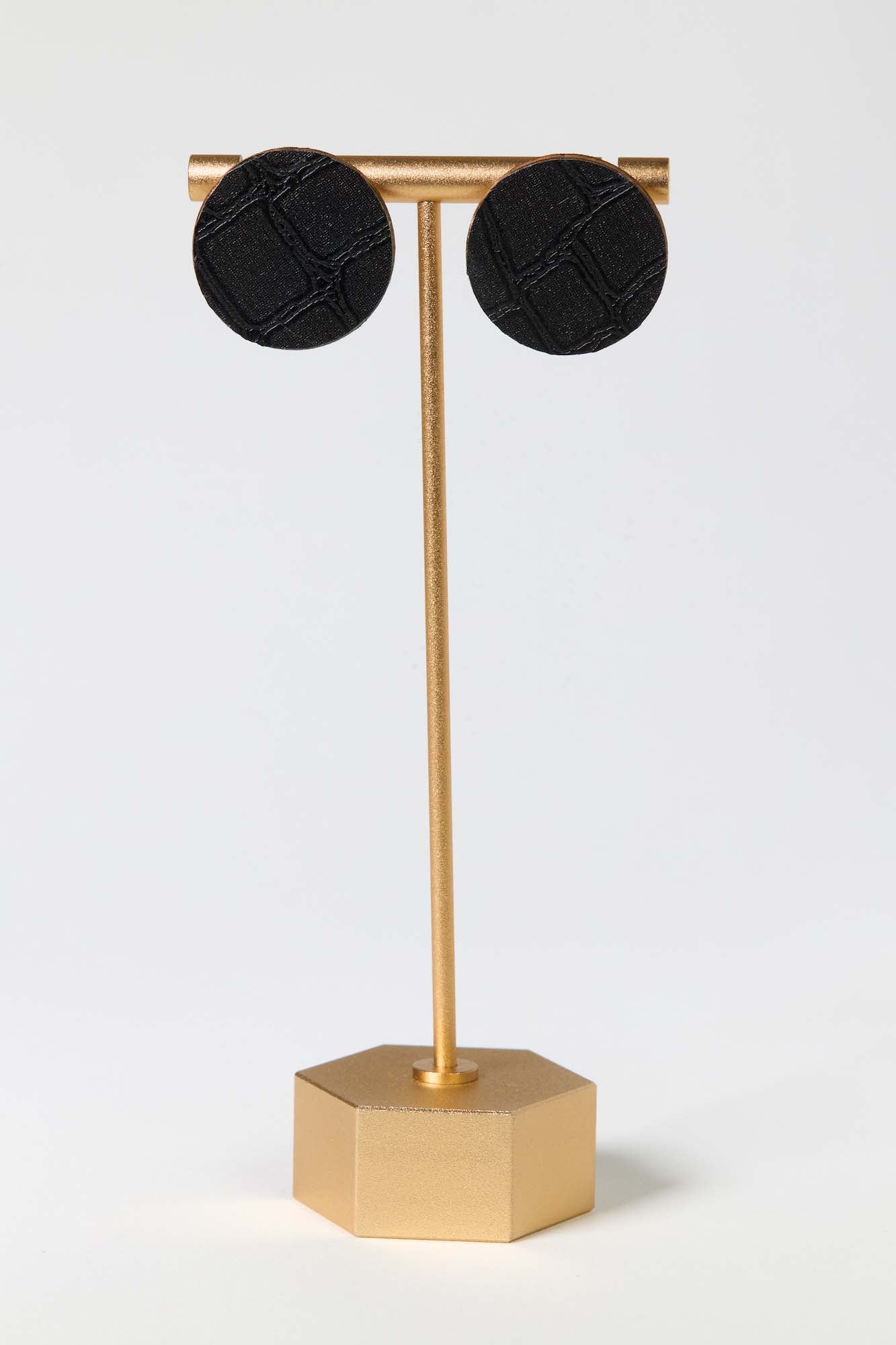 Black earrings on a gold stand against a white background