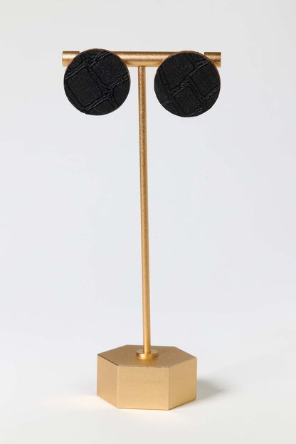 Black earrings on a gold stand against a white background