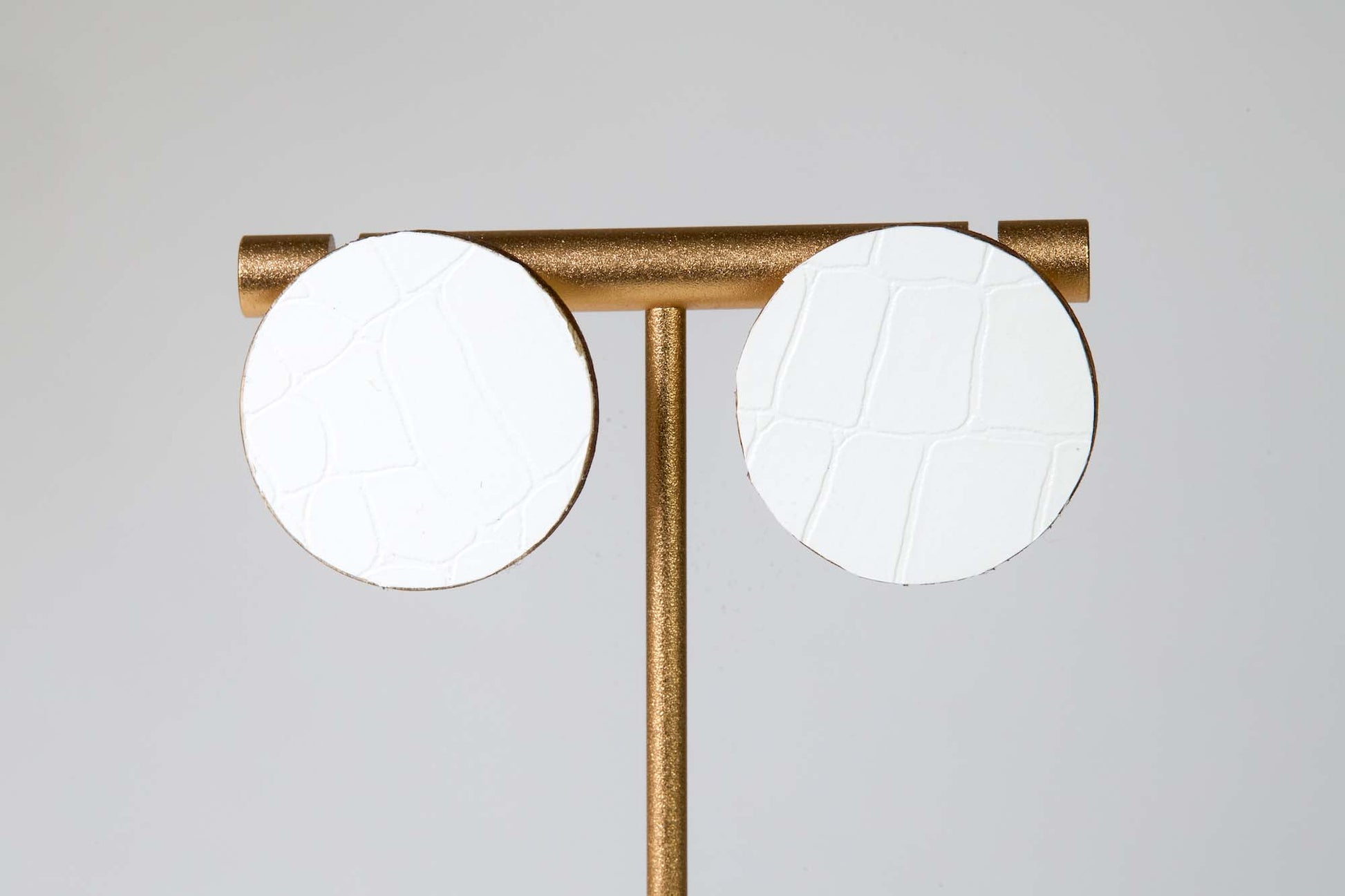 Modern ceiling light fixture with two round white lights on a gold frame against a gray background
