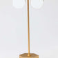 Gold lamp with two round white lights on a light gray background