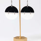 Black and white earrings on a gold stand against a white background