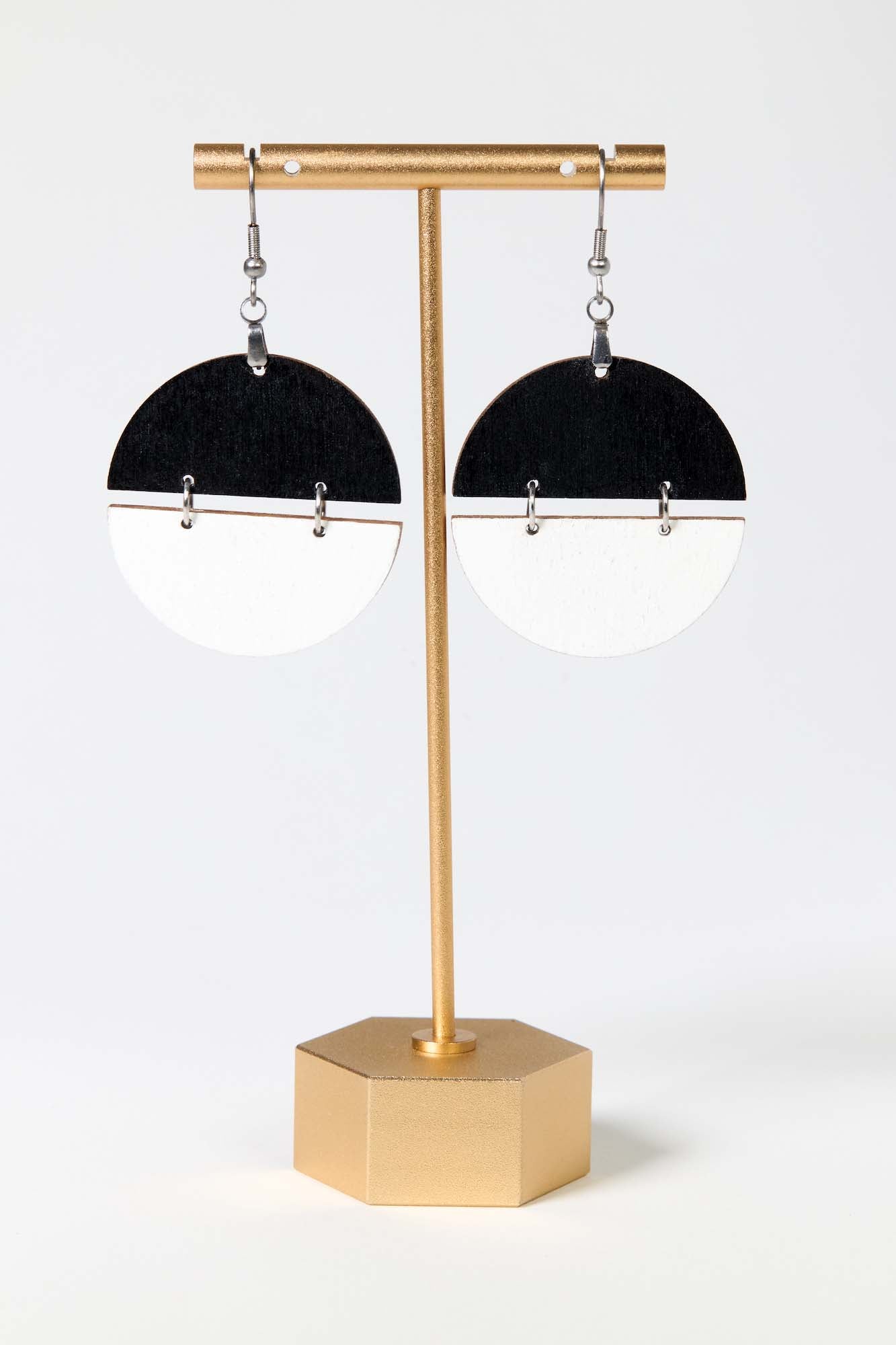 Black and white earrings on a gold stand against a white background