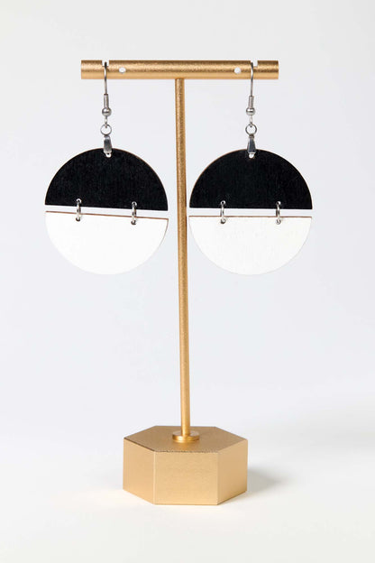 Black and white earrings on a gold stand against a white background