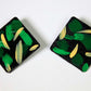 Pair of square earrings with green and beige abstract design on a white background