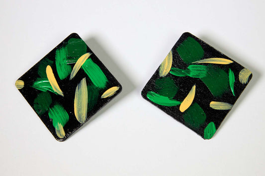 Pair of square earrings with green and beige abstract design on a white background