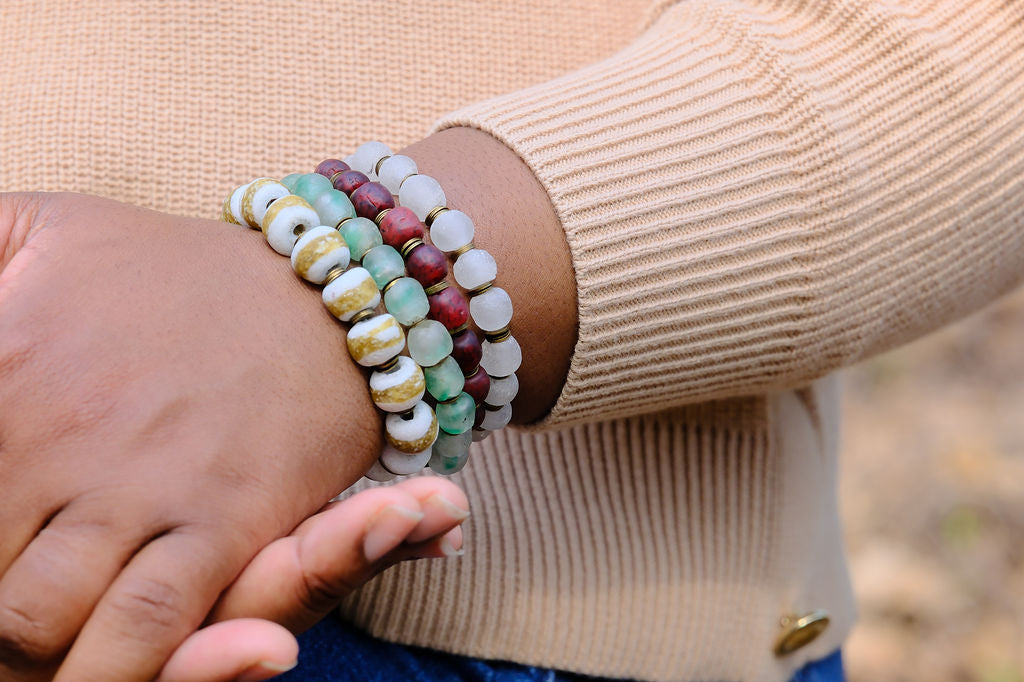 Person wearing a stack of colorful beaded bracelets on a blurred background