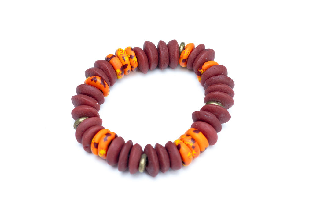 A multicolored bead bracelet with a mix of brown, orange, and yellow hues, featuring brass donut beads and fused rondelle African recycled glass beads against a white background.