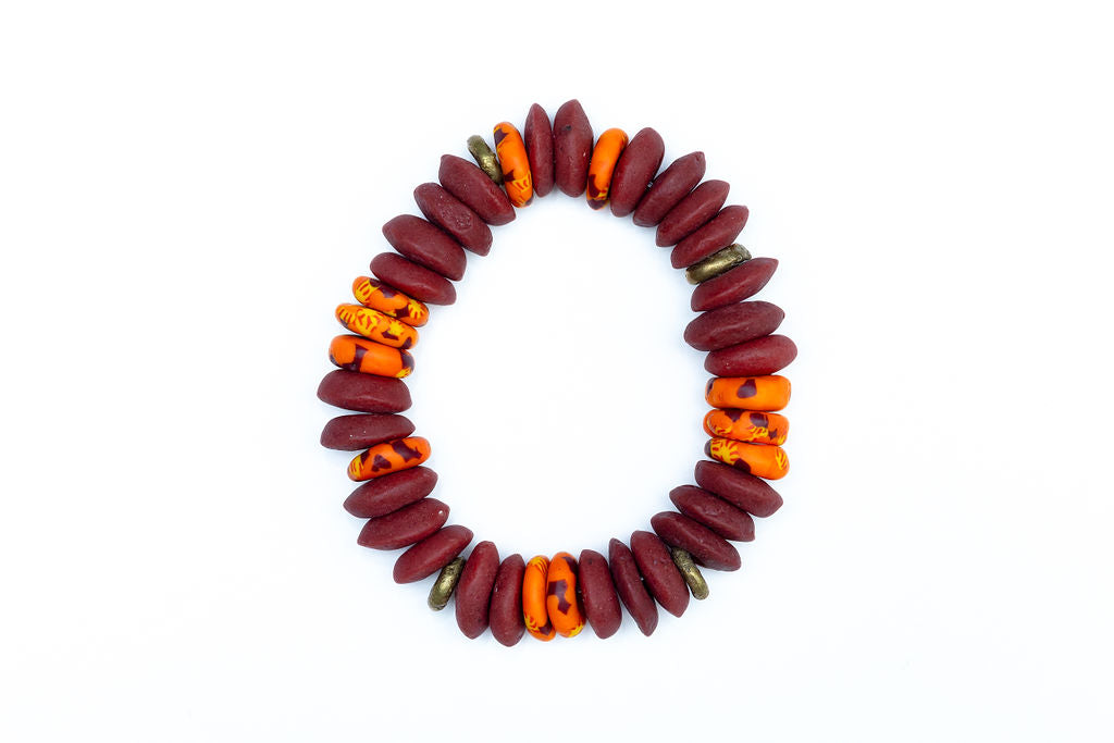 A multicolored bead bracelet with a mix of brown, orange, and yellow hues, featuring brass donut beads and fused rondelle African recycled glass beads against a white background.
