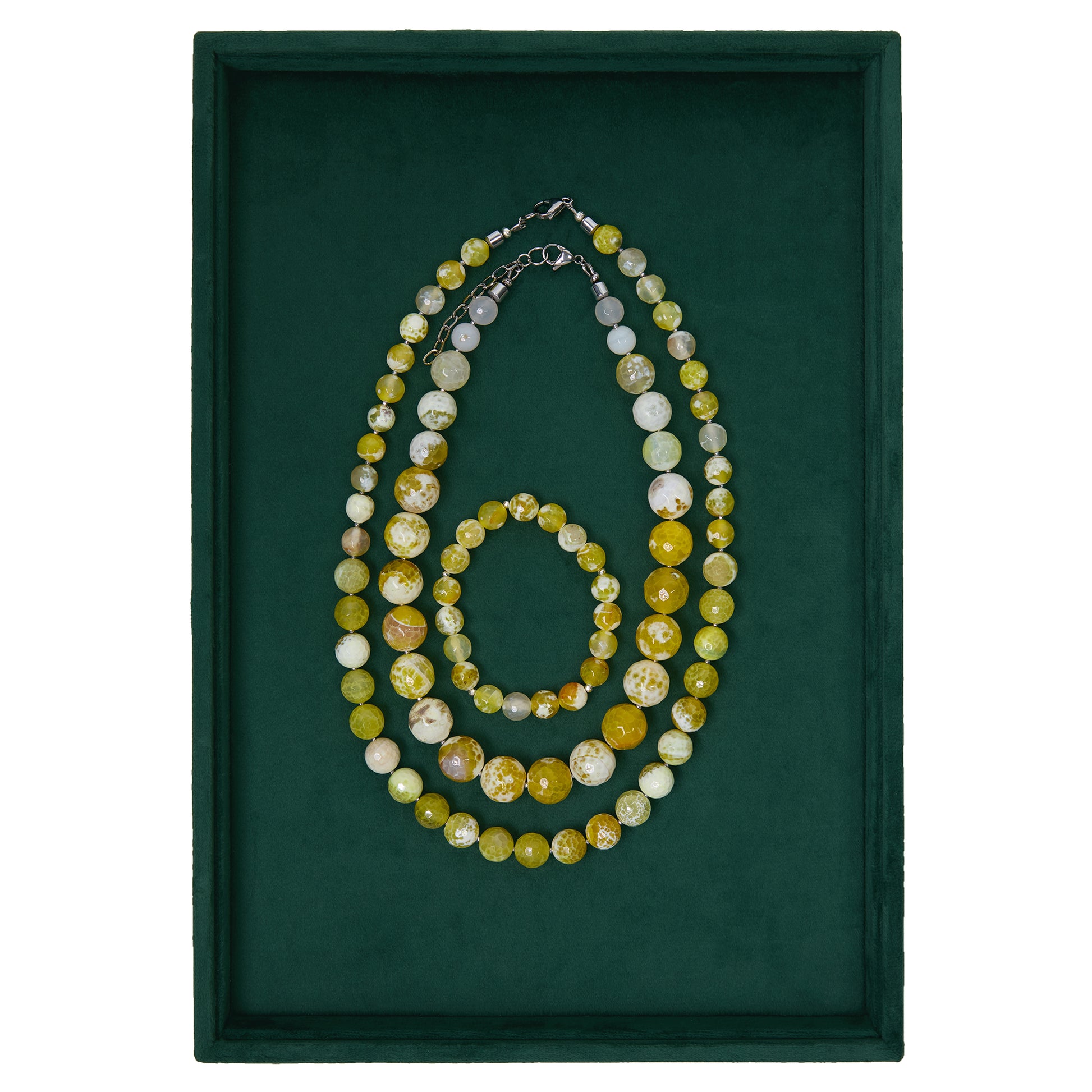 Set of beaded necklaces and bracelet on a green background