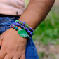 Person wearing colorful beaded bracelets on a blurred natural background