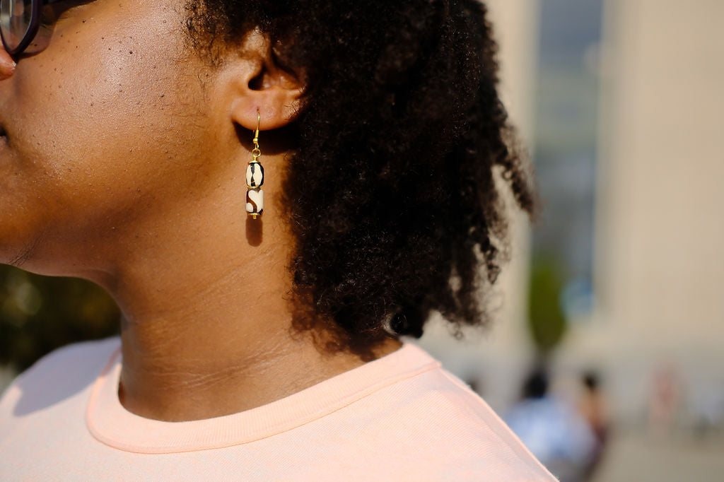 Close-up of a person wearing gold earrings with a blurred background