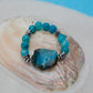 Turquoise beaded bracelet with a large blue stone on a seashell.