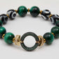 Bracelet with green and black beads and a gold, green, and black connector on a white background